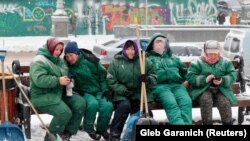 Столичні комунальниці перепочивають після чищення снігу лопатами у центрі Києва. 8 лютого 2021 року
