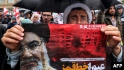 A Shi'ite Muslim cleric holds a poster reading "crossing a red line" in Persian next to an image of Hassan Nasrallah during an anti-Israel protest in Tehran's Palestine Square on September 28.