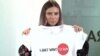 Krystsina Tsimanouskaya, who flew to Warsaw under Polish diplomatic protection, holds up a T-shirt after speaking with reporters upon her arrival in the city on August 5. 