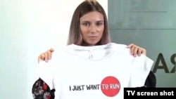 Krystsina Tsimanouskaya, who flew to Warsaw under Polish diplomatic protection, holds up a T-shirt after speaking with reporters upon her arrival in the city on August 5. 