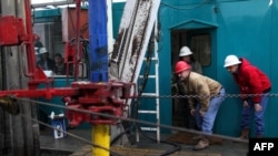 Floor hands and engineers adjust a down-hole motor used for directional drilling on a gas-drilling platform in the Barnett Shale near Fort Worth, Texas.