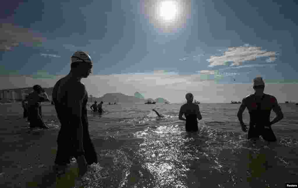 Swimmers enter the water before the start of the men's 10-kilometer marathon swimming final.