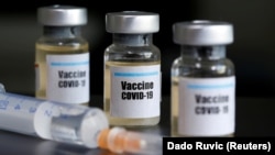  Бутылочки с наклейкой «Вакцина COVID-19» и медицинский шприц.