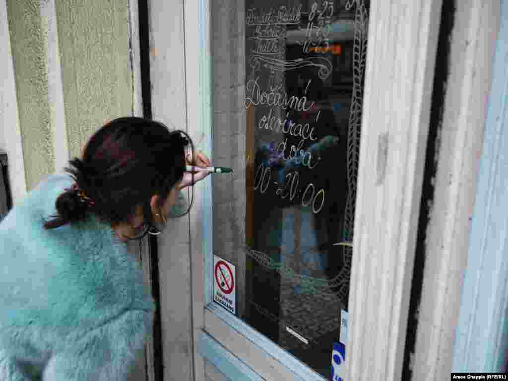 A waitress writes the new opening hours of her cafe in Nusle. From March 13, restaurants and bars were required to close by 8 p.m. On March 14, the Czech government declared such businesses must shut down completely for ten days.&nbsp;