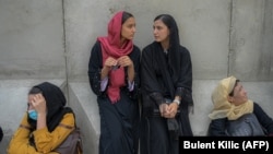 Afghan women wait in front of a bank office in Kabul on September 20, weeks after the Taliban seized power.