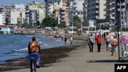 Луѓе шетаат на плажа во Драч