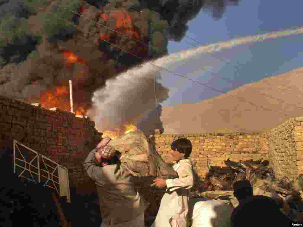 Men remove logs from near the site of 20 burning oil tankers that were carrying supplies to foreign forces in Afghanistan, after they were attacked in the outskirts of Quetta on October 6. Photo by Reuters