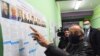 Борис Вишневски от опозиционната партия Яблоко показва таблото в избирателната си секция в Санкт-Петербург. На него се виждат трима кандидати с неговото име, двама от които са сменили и външността си, за да приличат на него.