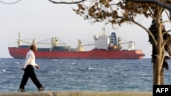 A man walks on the seafront promenade in Limassol as the Russian-owned cargo ship "Monchegorsk" is docked offshore. (file photo)