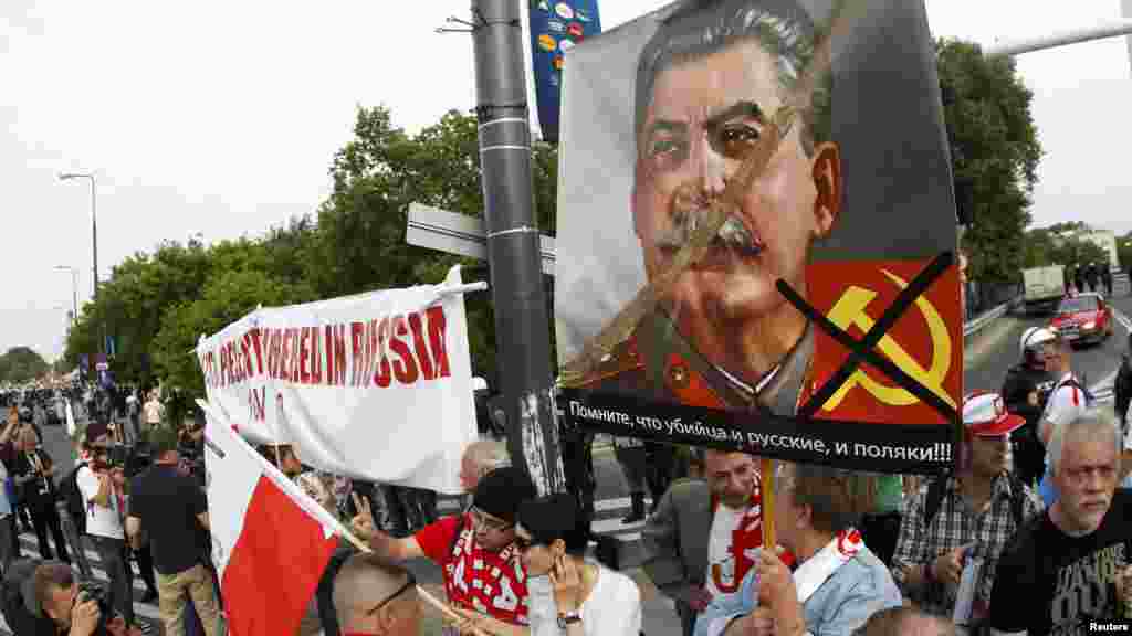 Polish protesters walk with a placard reading &quot;Russians and Poles, remember who is the killer!&quot; and depicting Soviet dictator Josef Stalin during a rally in Warsaw.
