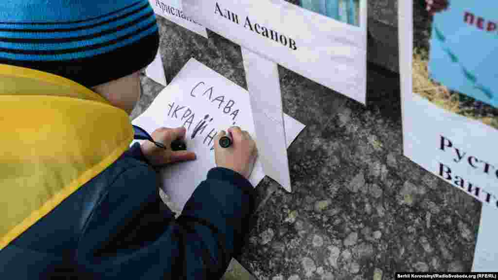 Хлопчик пише гасло &laquo;Слава Україні!&raquo;, щоб залишити його біля посольства