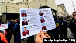 Демонстрат на вчерашните протести држи фотографии од судиите кои ја донесоа пресудата со која беа ограничени овластувањата на Националната антикорупциска агенција