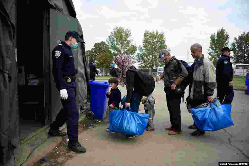 Porodica stoji ispred šatora u prihvatnom centru u Opatovcu, pored grada Tovarnik u Hrvatskoj.Ovdje se vrši registracija izbjeglica koje su iz Srbije došle u Hrvatsku. Nakon registracije, izbjeglice nastavljaju put prema Sloveniji, većina izbjeglica želi da stigne u Njemačku.