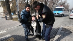 Полиция өкілдері ұстаған адамды "Астана" алаңы маңында тұрған көлікке салуға әкеле жатыр. Алматы, 22 ақпан 2020 жыл.