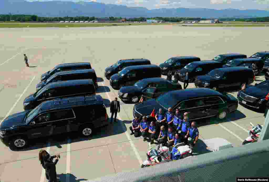 Сотрудники женевской полиции фотографируются на фоне кортежа, который будет сопровождать по прилету автомобиль президента США