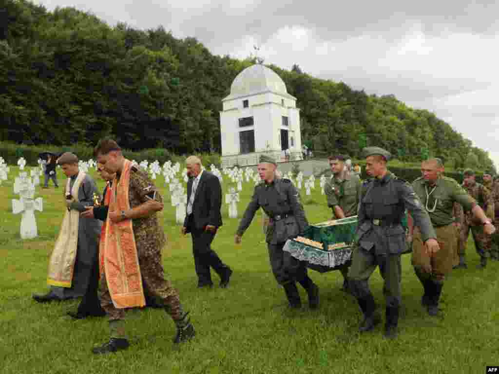 Activists of the Pamiat, or Memory Searching Organization, for victims of World War II, carry the coffin with the remains of Ukrainian, German, and Soviet soldiers of the "Galician" SS Division during a reburial ceremony near Chervone, some 70 kilometers from the western Ukrainian city of Lviv, on July 24. Photo by Yuriy Dyachyshyn for AFP