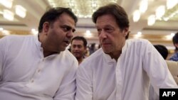 Fawad Chaudhry (left) speaks to Imran Khan in 2018.