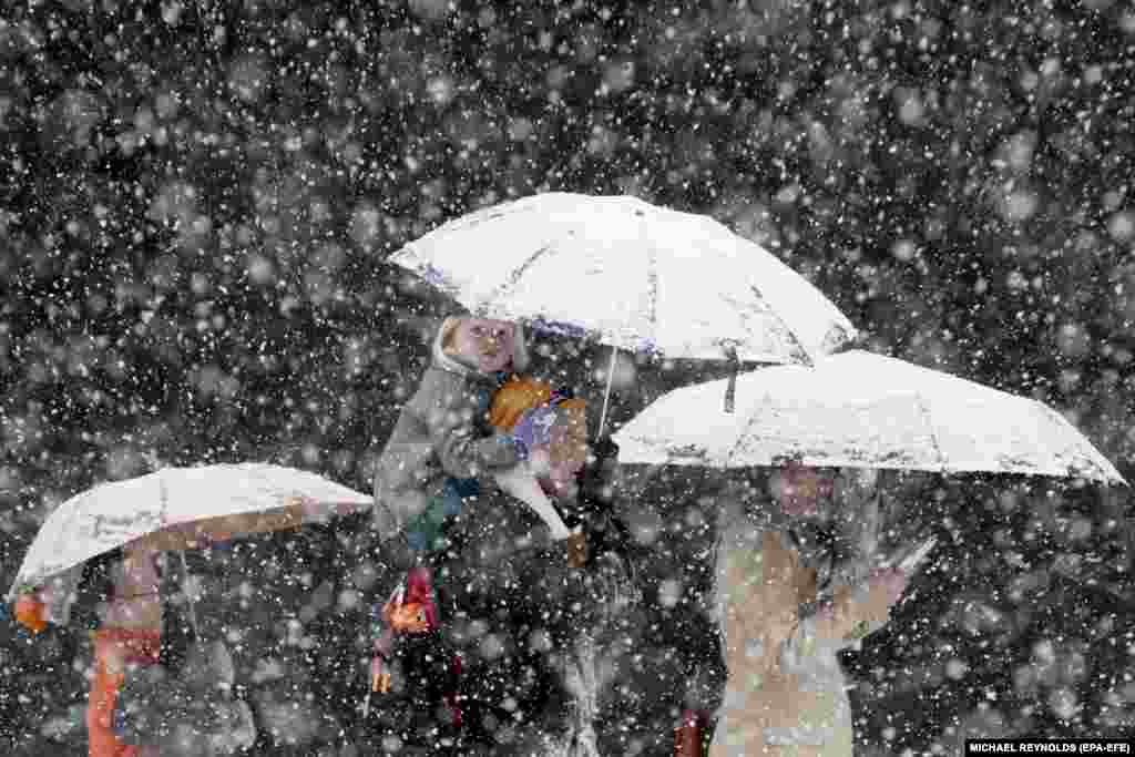 A little girl is carried on the shoulders of a man as people walk in the snow in downtown Washington on March 21. (epa-EFE/Michael Reynolds)