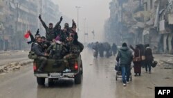 Syrian pro-regime fighters gesture as they drive past residents fleeing violence in Aleppo.