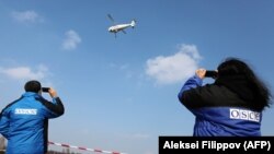 OSCE observers watch a test flight of a surveillance drone along the eastern front line in Ukraine's Donetsk region last year.
