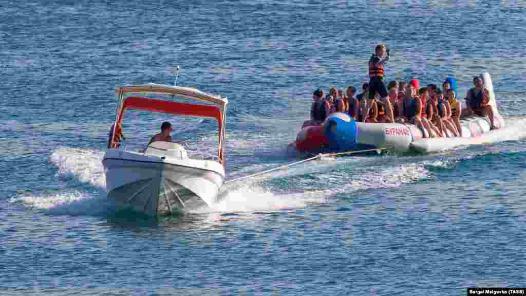 Отдыхающие в Судаке катаются на надувной лодке по Черному морю&nbsp;