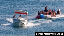 Отдыхающие катаются на надувной лодке по Черному морю, иллюстрационное фото