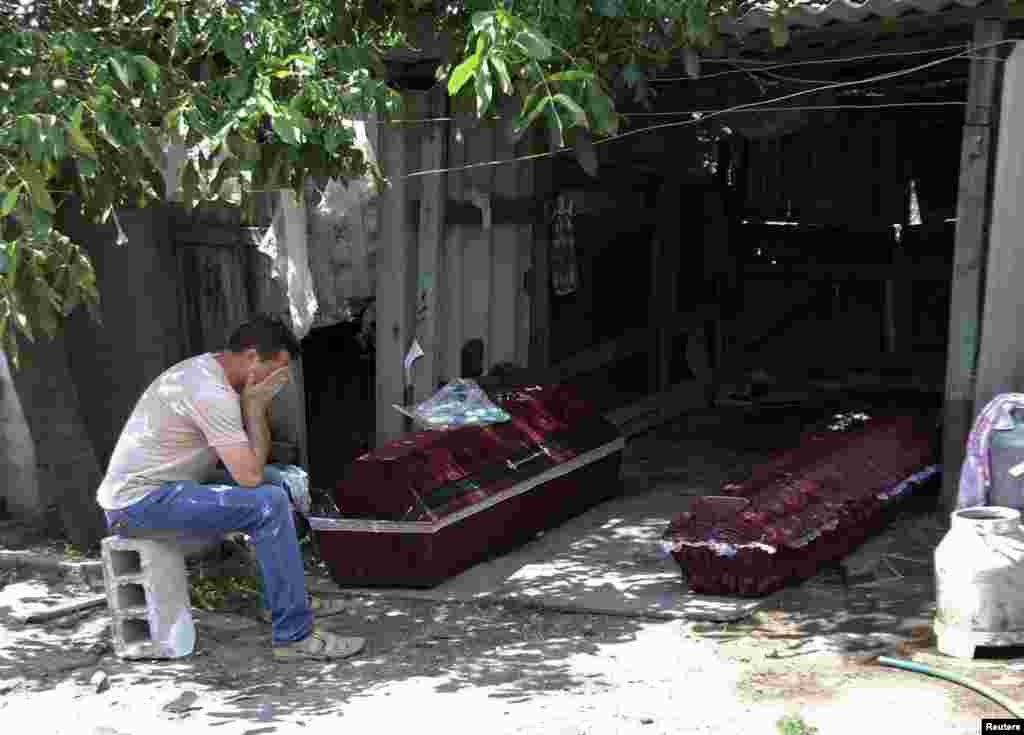 A man whose mother was killed by shelling, according to locals, reacts while sitting near her coffin outside her damaged house before her funeral in Donetsk on July 7. (Reuters/Igor Tkachenko)
