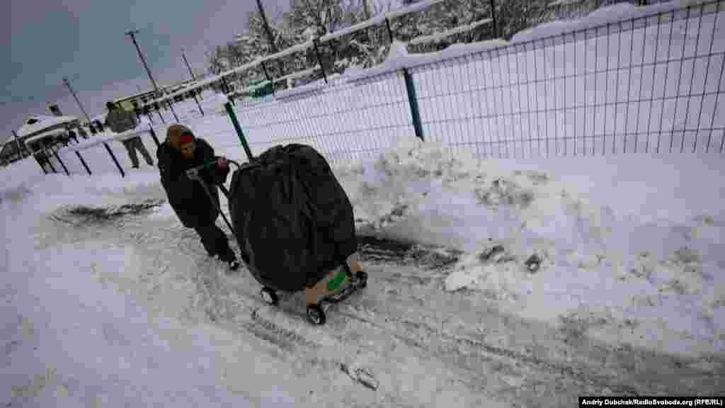 Nikolayevna at work, pushing a load of fruits and vegetables through slushy snow toward separatist-held territory. Such fresh items are significantly more expensive in the separatist region. 