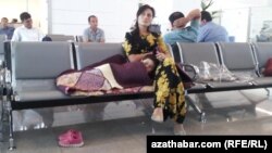 Türkmenistanyň aeroportlarynyň birinde oturan zenan we onuň çagasy. Arhiwden alnan surat