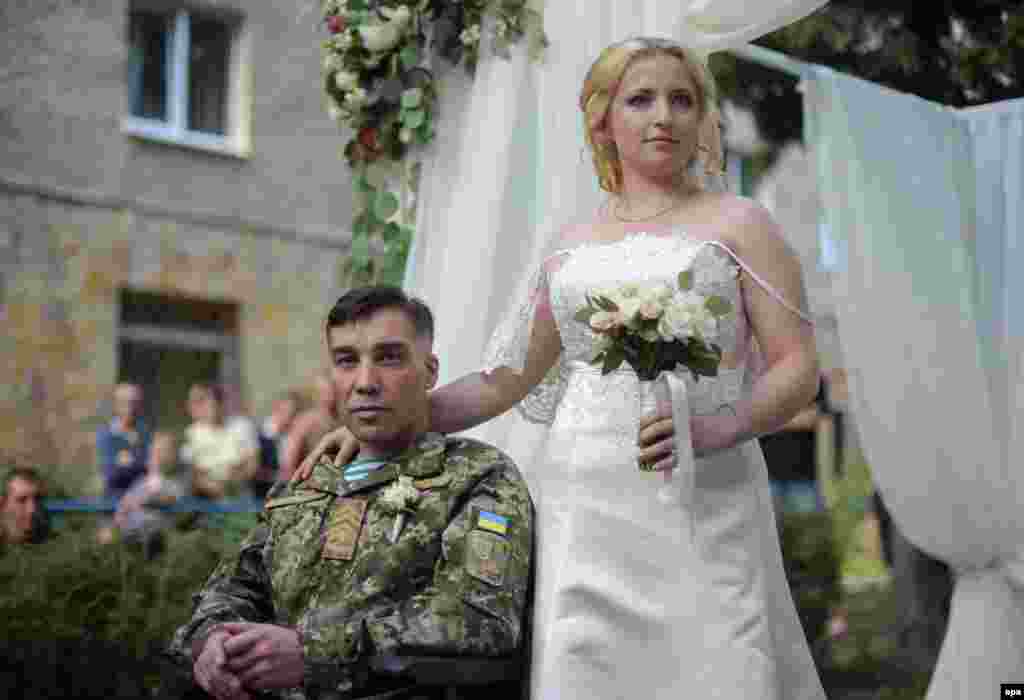 Ukrainian serviceman Sergiy Yushchenko (left) and his bride, Kateryna, at their wedding in the military hospital in Lviv. Sergiy was wounded and paralyzed during fighting with pro-Russia militants. (epa/Markiian Lyseiko)