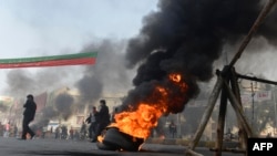 Activists of Imran Khan's Pakistan Tehrik-e Insaaf (PTI) party block a road with burning tires during an antigovernment protest in Lahore on December 15.