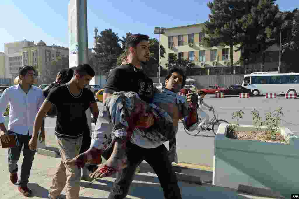 An Afghan man carries a victim away from the scene of a suicide attack in central Kabul. At least three foreign troops were killed. (AFP/Shah Marai)