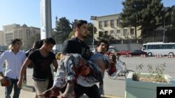 Afghanistan -- An Afghan man carries a wounded man at the site of a suicide attack in Kabul, September 16, 2014