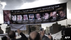 Egypt -- Protesters take pictures of a banner with portraits of members of President's regime on Tahrir Square in Cairo, 10Feb2011