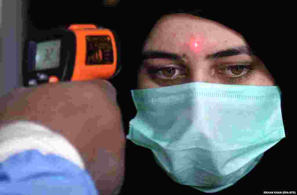 A railway staff checks temperature of a passenger as railway authorities resume the train operations, after the government eased coronavirus restrictive measures, in Karachi, Pakistan, 20 May 2020. Several countries around the world have started to ease COVID-19 pandemic lock-down restrictions in an effort to restart their economies and help people in their daily routines after the outbreak of coronavirus pandemic.