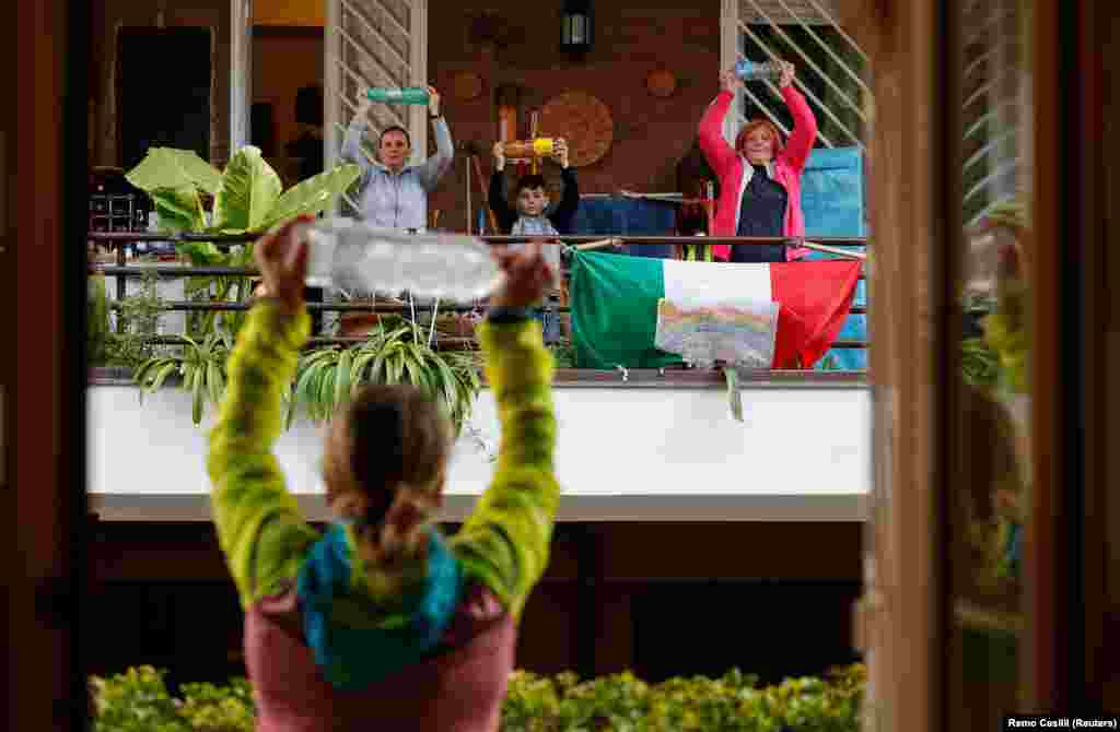 With Italians unable to leave their homes due to the coronavirus, a personal trainer leads an exercise class for her neighbors from her balcony in Rome. (Reuters/​Remo Casilli)