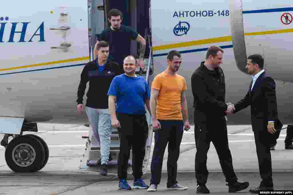 Ukrainian President Volodymyr Zelenskiy (right) welcomes former prisoners as they disembark from a plane on September 7 at Boryspil International Airport in Kyiv after a long-awaited exchange of prisoners between Moscow and Kyiv.