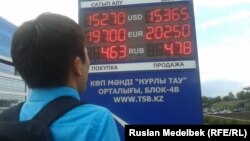 Молодой человек смотрит на табло обменного пунка. Алматы, 23 июля 2013 года.