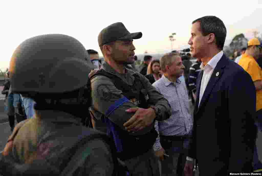 Venezuelan opposition leader Juan Guaido, whose claim to the presidency is backed by the United States and other countries, speaks with a man in uniform near the air base shortly after sunrise in the Venezuelan capital.&nbsp;