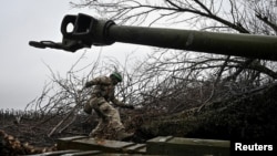 Український військовослужбовець батальйону спеціального призначення Національної поліції України готується стріляти з гаубиці поблизу міста Покровськ, Донецька область