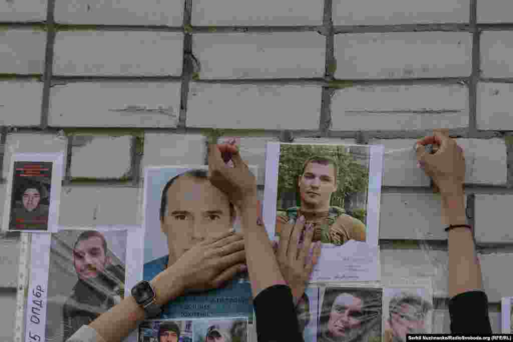Люди прикріплюють фотографії українських військових, які зникли безвісти