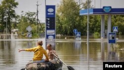 Місцеві жителі пливуть на човні вулицею під час евакуації із затопленої території після прориву дамби Нової Каховки в Херсоні, 7 червня 2023 року, ілюстративне фото