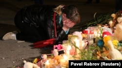 Жінка оплакує загиблих біля тимчасового меморіалу біля місця нападу на коледж у портовому місті Керч, 17 жовтня 2018 року