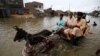 People make their way through a flooded road from heavy monsoon rains in Karachi on August 12.