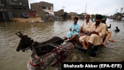 People make their way through a flooded road from heavy monsoon rains in Karachi on August 12.