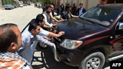 Afghan security personnel and police push the vehicle from which a German female aid worker was kidnapped by armed gunmen at the entrance to the office of German development agency GIZ in Kabul on August 17.