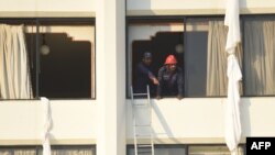 Pakistani firefighters look from a room of the Regent Plaza Hotel where bedsheets were tied together by guests in an effort to escape the flames.