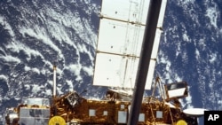 The STS-48 onboard photo of the Upper Atmosphere Research Satellite (UARS) in the grasp of the RMS (Remote Manipulator System) during deployment in September 1991.