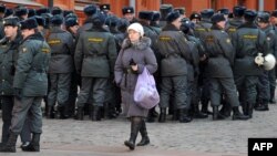 A woman walks past police officers gathering just outside the Kremlin in Moscow on March 2.