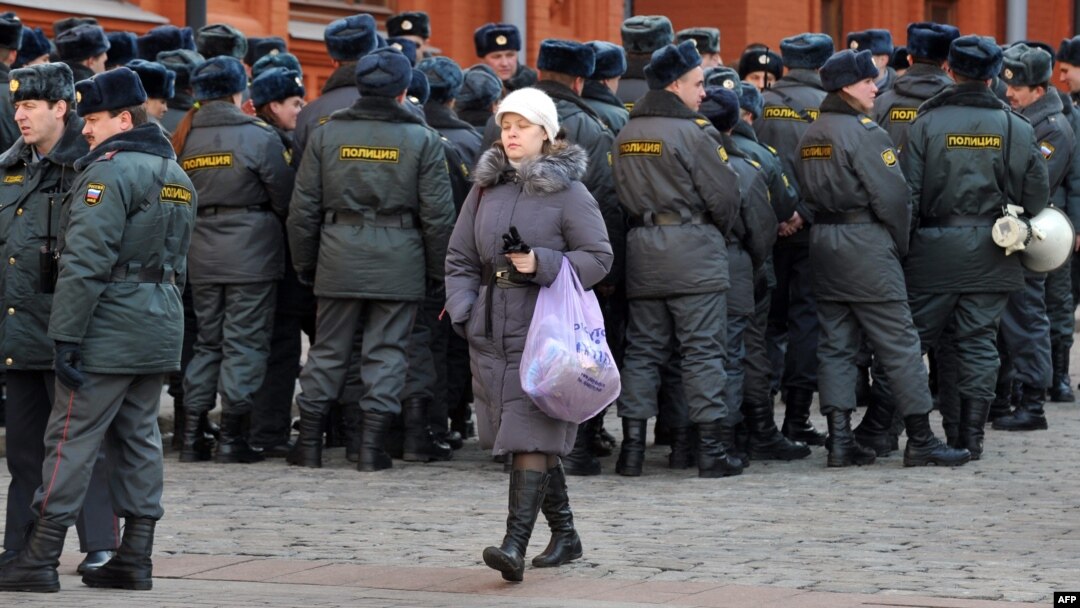 A woman walks past police officers gathering just outside the Kremlin in Moscow on March 2.